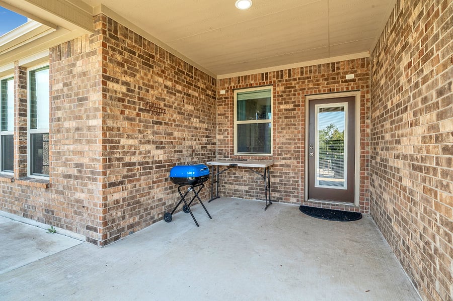 Covered back patio with grill and seating, opening to a spacious backyard with fire pit and chairs. The yard is fully fenced, with a wrought iron pin fence along the back that overlooks the lake. Once leaves fall, the entire back transforms into a full lake viewperfect for relaxing or entertaining.