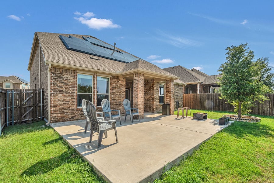 Covered back patio with grill and seating, opening to a spacious backyard with fire pit and chairs. The yard is fully fenced, with a wrought iron pin fence along the back that overlooks the lake. Once leaves fall, the entire back transforms into a full lake viewperfect for relaxing or entertaining.