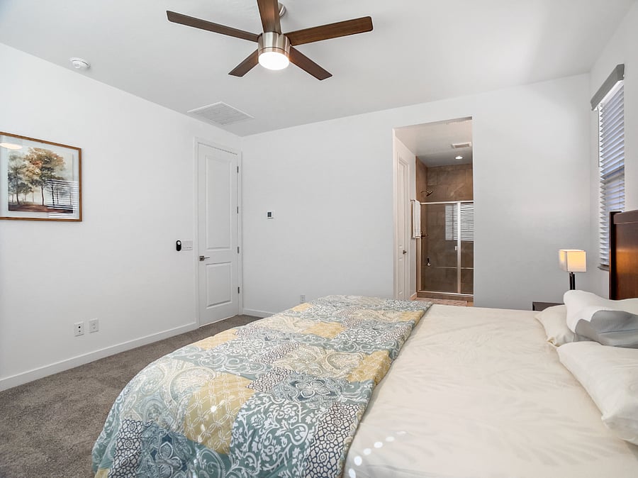 Master bedroom with a brand-new king-size memory foam bed, two night stands with bedside lamps, ceiling fan, attached walk-in bathroom with double vanity sinks, and a spacious walk-in closet.