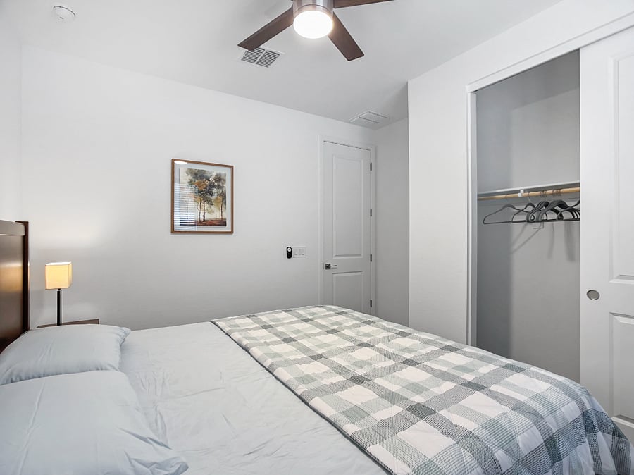 2nd bedroom attached to the second suite with a brand-new king-size memory foam bed, two bedside lamps, ceiling fan, private full bathroom, and storage closet.