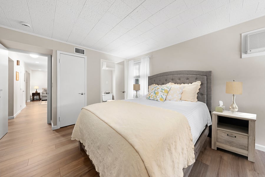 Larger bedroom: Spacious, with a comfortable queen bed and new furnishings. The doorway beside the bed leads to its private half bath.