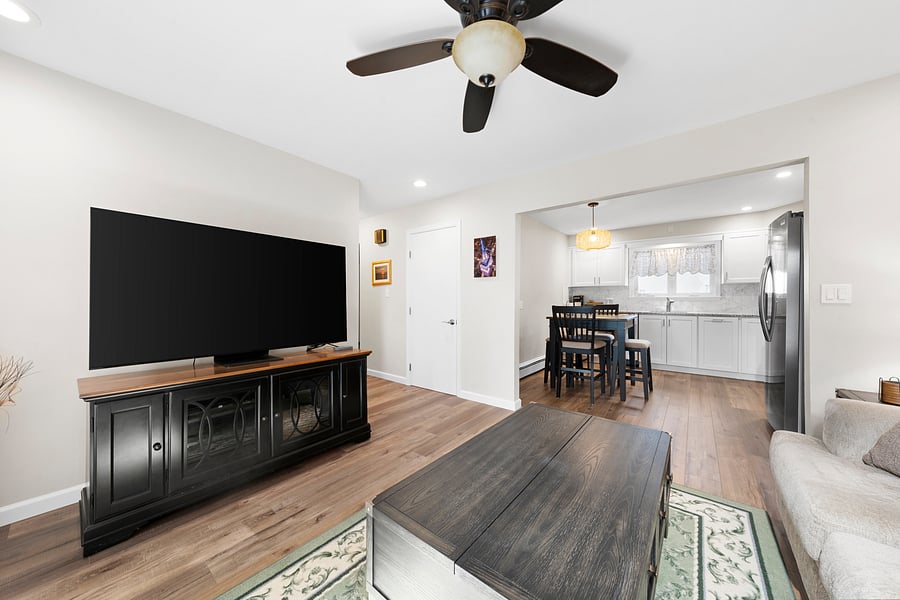 Another view of the living room, showing the 60-inch smart TV and its open connection to the fully equipped kitchen with pub-height seating for four.