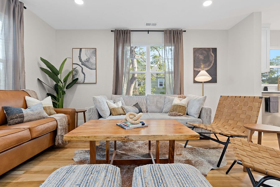 Modern living room with natural light, clean lines, and updated furnishings. Features leather seating, woven chairs, and neutral decor. Ideal for short-term stays with cozy, clean, and stylish design perfect for remote work or relaxing.