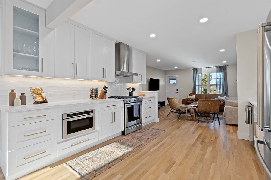 Fully equipped modern kitchen with stainless steel appliances, clean white cabinetry, and open layout. Ideal for short-term stays with updated cooking essentials, hardwood floors, and seamless flow to living area for remote work or group travel.