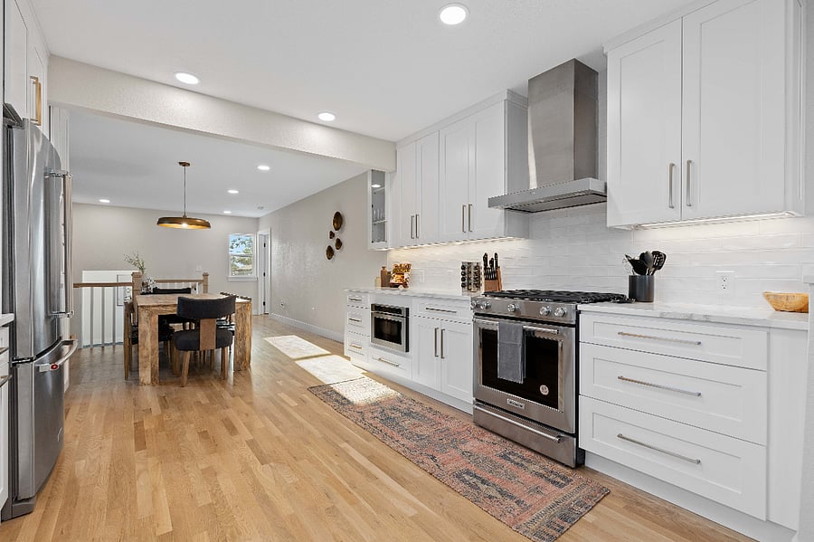 Fully equipped modern kitchen with stainless steel appliances, clean white cabinetry, and open layout. Ideal for short-term stays with updated cooking essentials, hardwood floors, and seamless flow to living area for remote work or group travel.