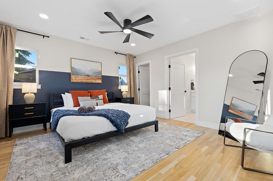 Spacious primary bedroom with clean bedding, modern decor, and ensuite access. Ideal for short-term stays with natural light, hardwood floors, and a minimalist setup perfect for comfort and privacy.