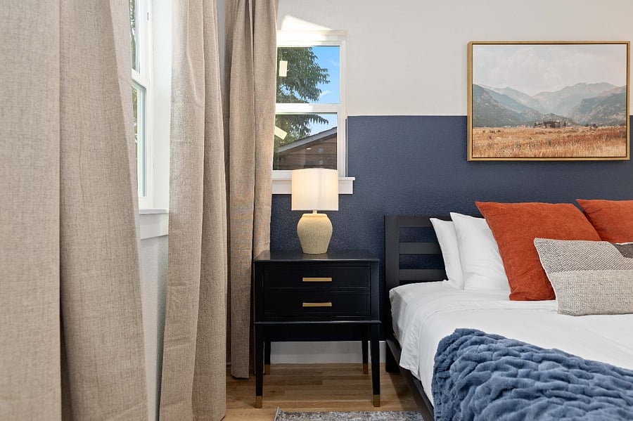 Clean bedroom detail with modern nightstand, soft lighting, and layered bedding. Perfect for short-term stays with cozy textures, natural light, and stylish touches for a comfortable night's rest.