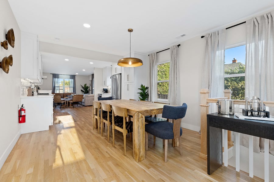 Spacious dining area with natural wood table, modern lighting, and clean finishes. Ideal for short-term rentals with ample seating, bright natural light, and an open layout for group dining or remote work.