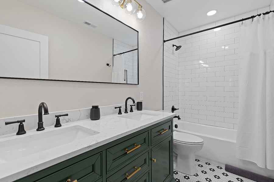 Modern bathroom with double vanity, matte black fixtures, and subway tile shower. Spotlessly clean and ideal for short-term rentals with updated finishes and stylish storage for group or family stays.