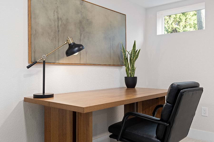 Minimalist home office setup featuring a sleek wood desk, matte black task lamp, and a modern leather chair. Ideal for remote work stays, this clean and inviting workspace adds function to your short-term rental.