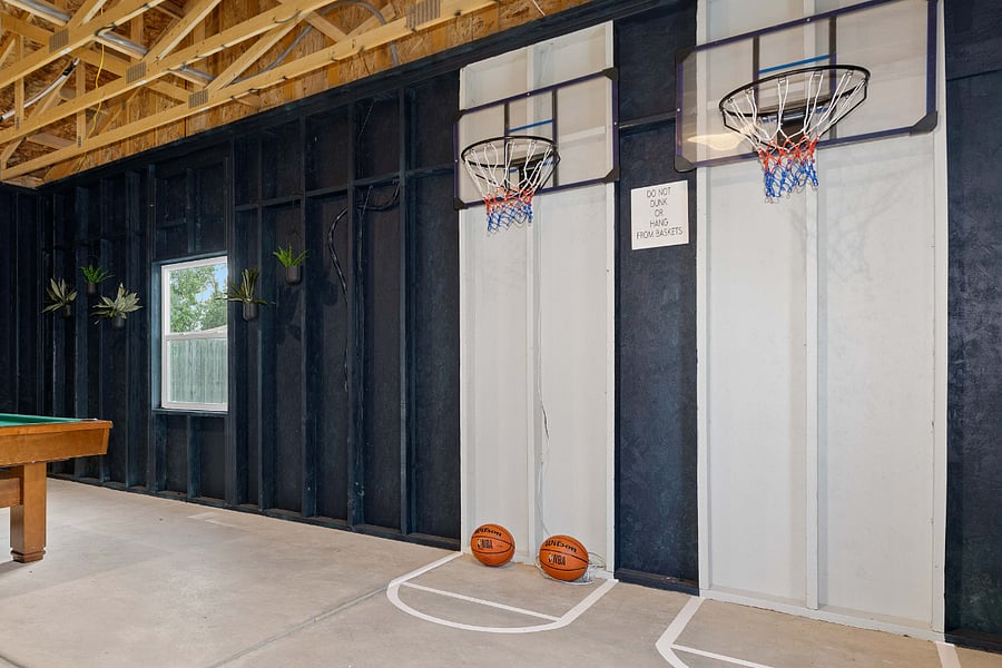 Enjoy friendly competition in the indoor game area featuring a full-size pool table and a custom mini basketball court with two hoops. A perfect space for entertainment and fun for all ages.