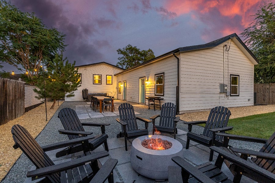 Secluded backyard with fire pit, Adirondack seating, and outdoor dining. Perfect for clean, private short-term stays with group-friendly amenities and relaxing evening gatherings under ambient lighting.