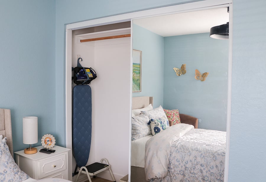 Full size ironing board and iron in the closet as well as a handy laundry basket and extra blanket