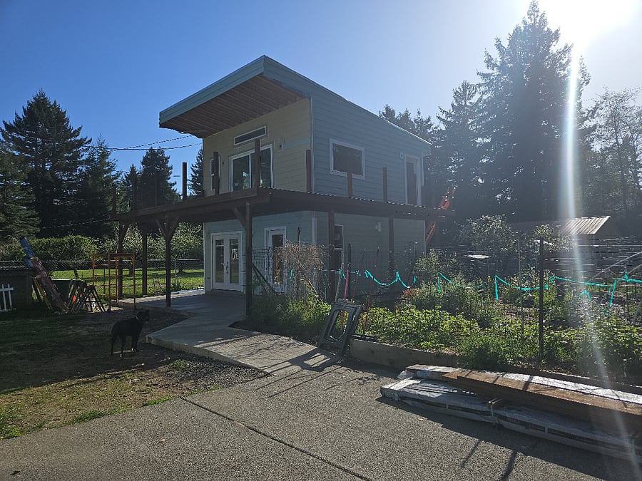 The house is surrounded by beautiful trees and a large veggie garden