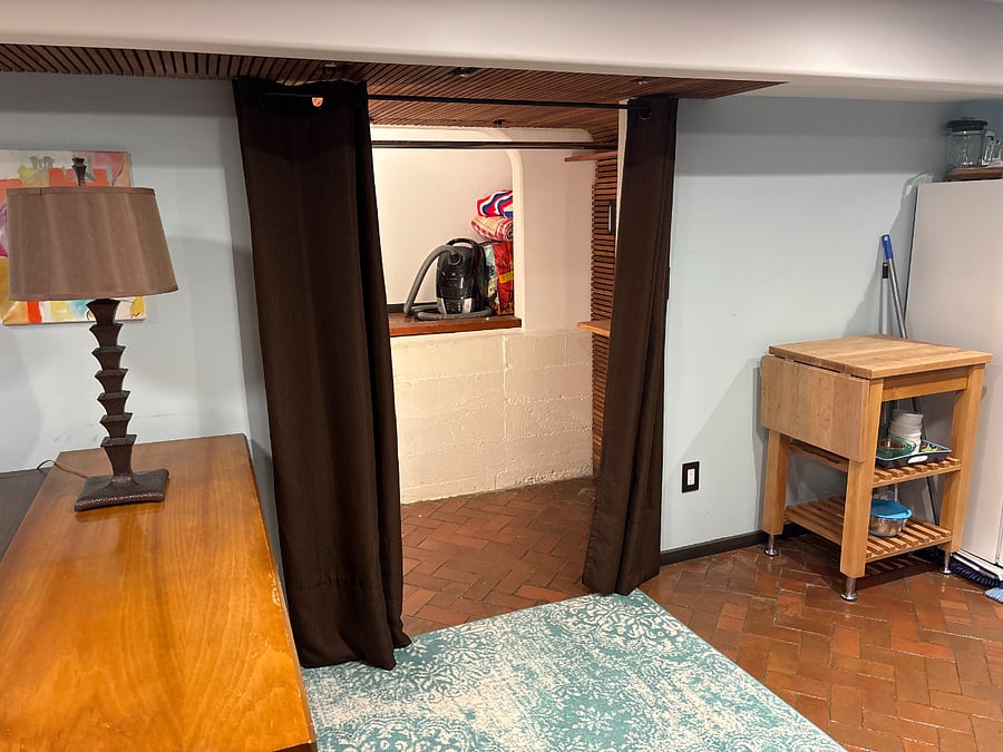 Deep Closet with storage behind clothing.  Apartment vacuum stored here.  