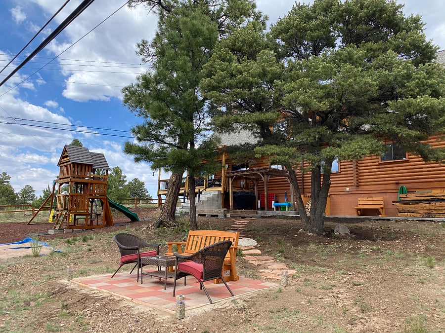 The large backyard offers a children's playset, a conversation space, and cornhole slabs.