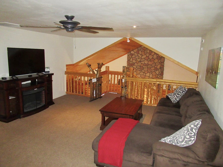 The upstairs loft features a sofa and TV, an upright game console, a foosball table and an air hockey table.