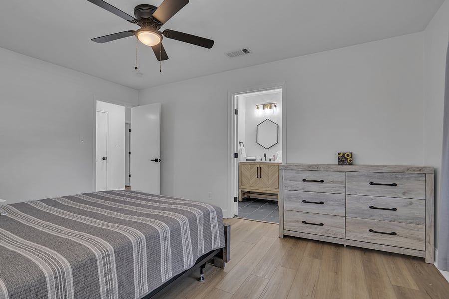 Guest bedroom with queen bed and dresser and ensuite