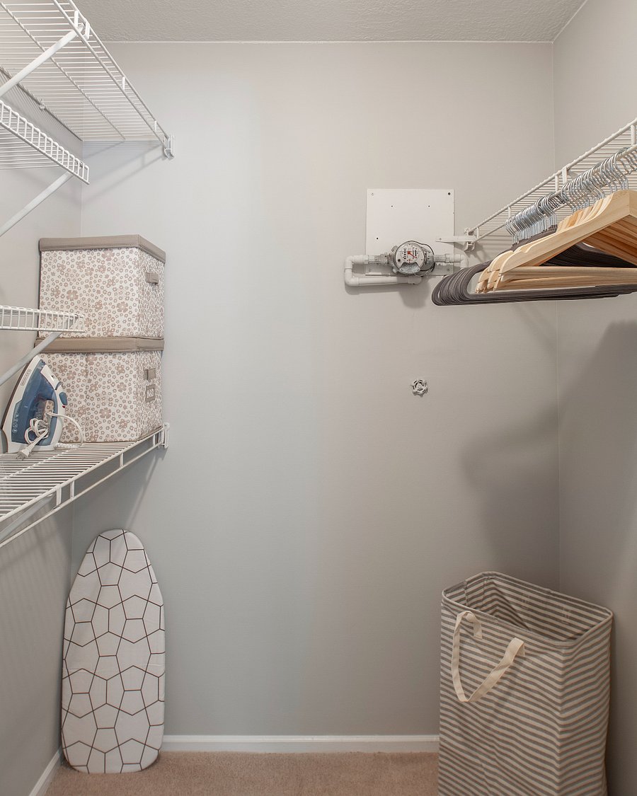 Lots of closet storage with hangers, iron and ironing board.