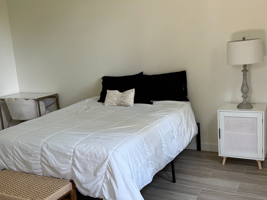 Master Bedroom has a queen bed with night stand , a lamp and a desk.