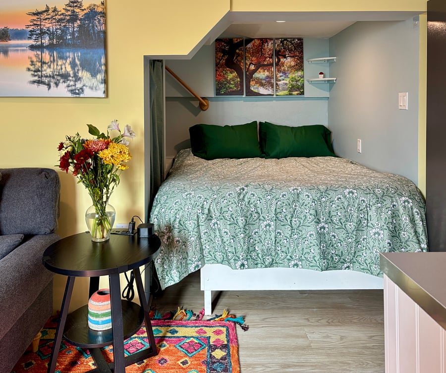 The comfortable queen bed is tucked in a cozy nook which has a closet on the left side and a small dresser.