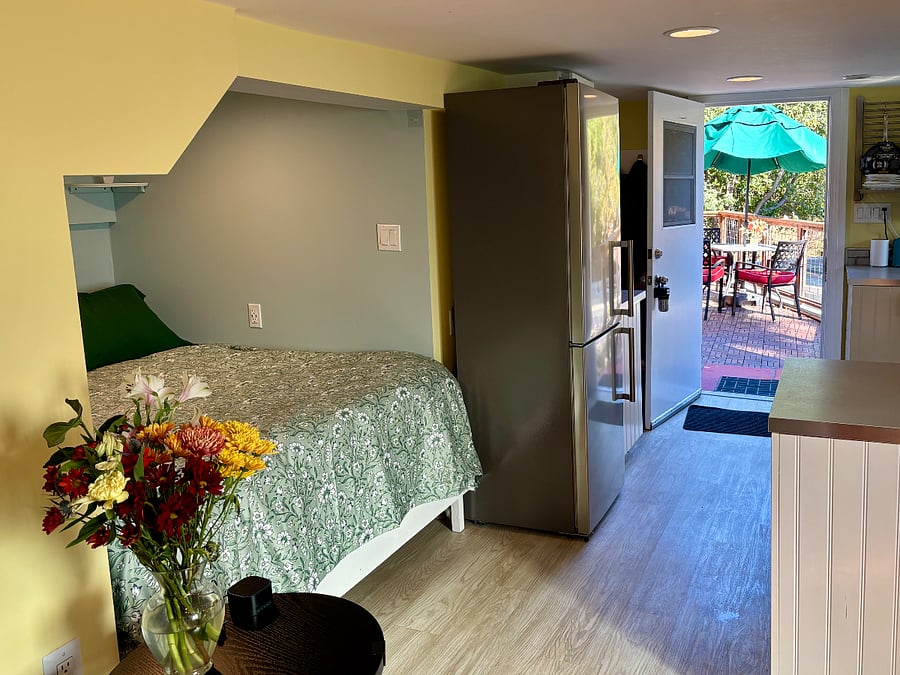 A view of the bedroom nook, with the kitchen and private outdoor patio beyond.