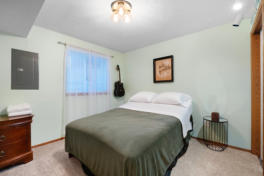 The musician's room features a queen bed, blinds, clothing storage, and closet space with hangers and a hamper.