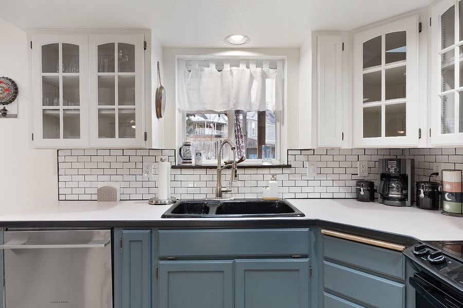 The Fisher & Paykel double drawer dishwasher makes cleanup a breeze. Above it, you'll find an 8-piece dinner and glassware for convenience. Below the sink are dishwasher tabs, trash bags, cleaning supplies, and a fire extinguisher.