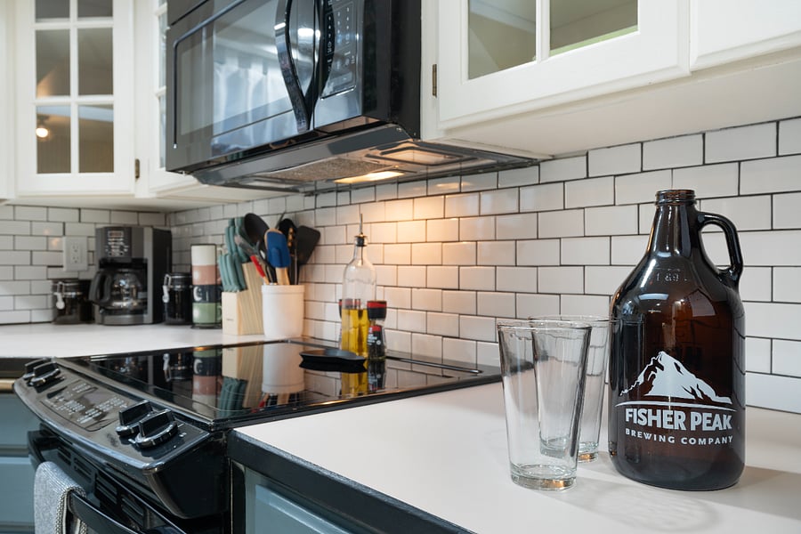 In the cabinets above, you'll find baking dishes, mixing bowls, a measuring cup, a strainer, a popcorn maker with popcorn provided, a salad spinner, large bowls, and a vase.
