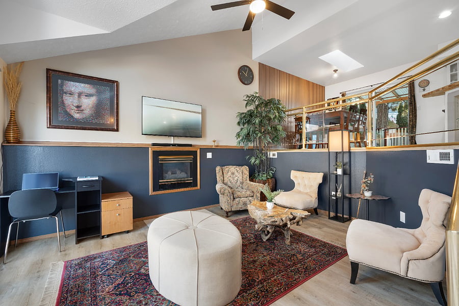 The living room features three wingback chairs and an ottoman, providing a cozy setup for easy conversation. With abundant natural light, this space offers a serene and quiet atmosphere to relax and unwind.