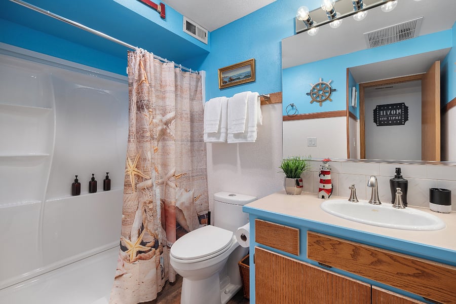 Downstairs bath offers a beach vibe with shower, toiletries, and body wash.