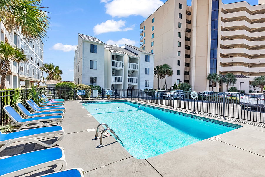 Poolside lounge chairs with Sea House Villas as the backdroprelax steps from your coastal retreat.