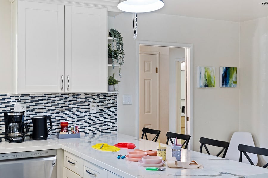 Various kitchen appliances and utensils on the countertop for kids. The kitchen also has a dining area with a table and chairs, creating a cohesive and functional living space.