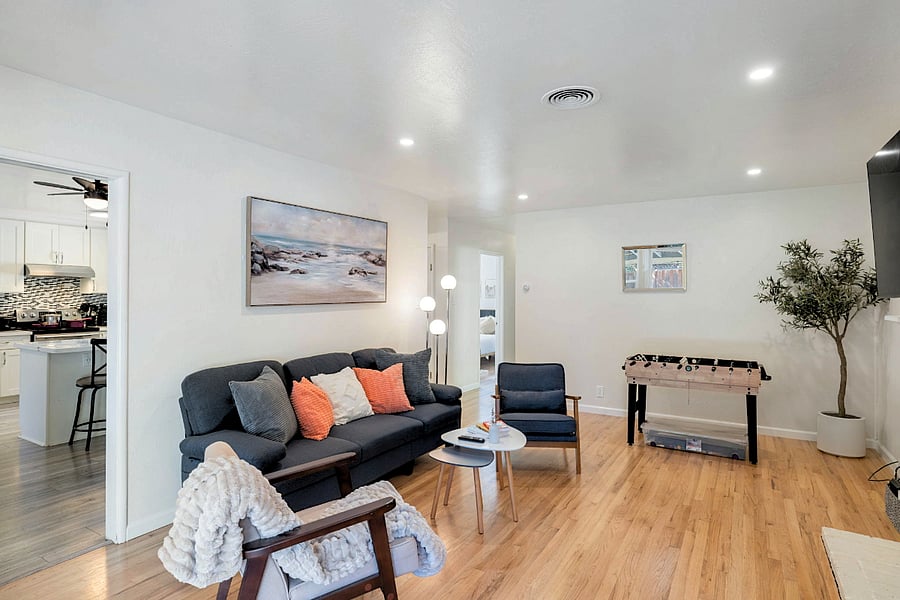 Comfortable living room with plush gray sofa, colorful pillows, wooden coffee table, foosball table, and stylish decor.