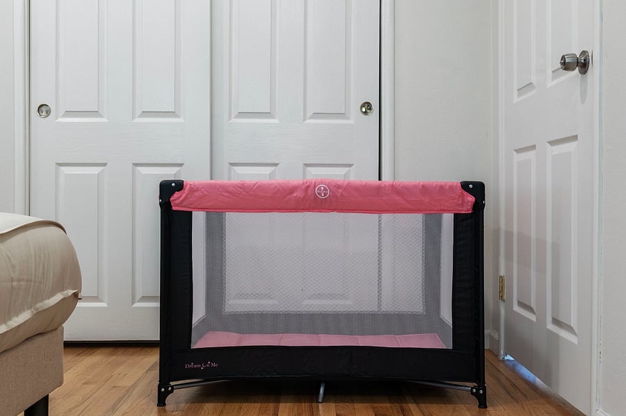 A pink and black portable baby playpen