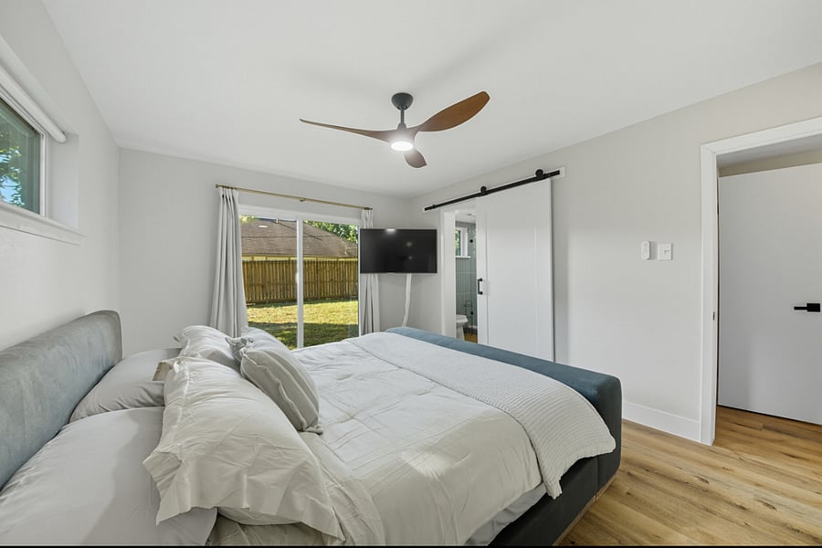 Downstairs bedroom with luxurious king bed, ensuite bath with custom walk in shower, and sliding glass doors to the backyard 