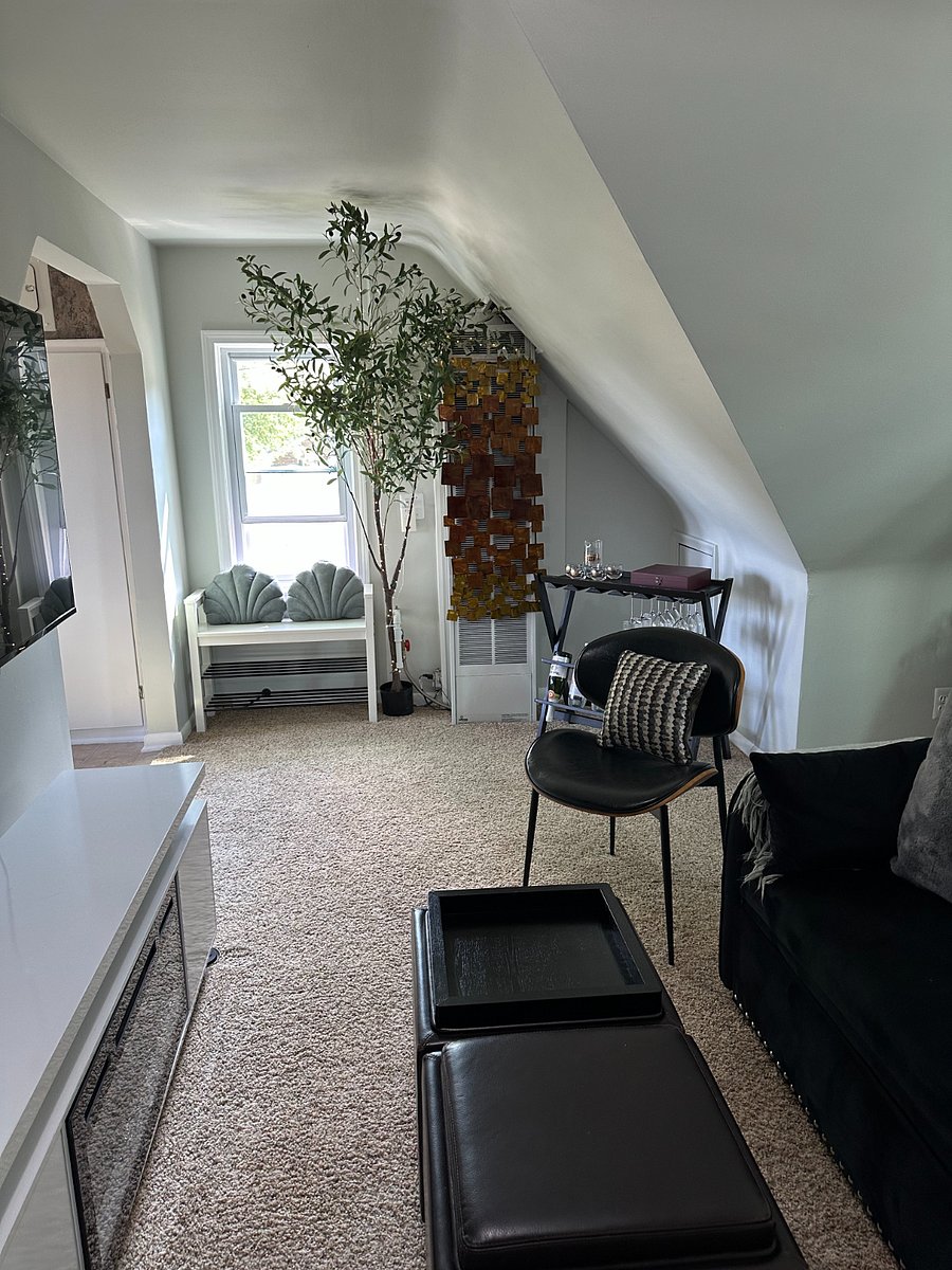 Additional view of the living room with window, bench, decorative artwork, and a tree with lighting offering a cozy atmosphere and additional storage/seating.  Enjoy a beverage from your portable wine bar.