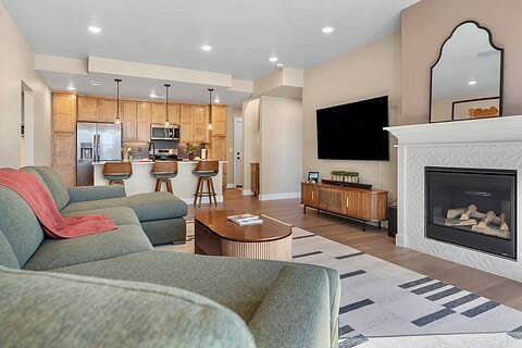 Comfortable living room with 14' lounger sofa, 70" Samsung Smart TV, matching sound bar & sub woofer, lift-top coffee table, board games, books, gas fireplace, and dimmable lighting throughout.