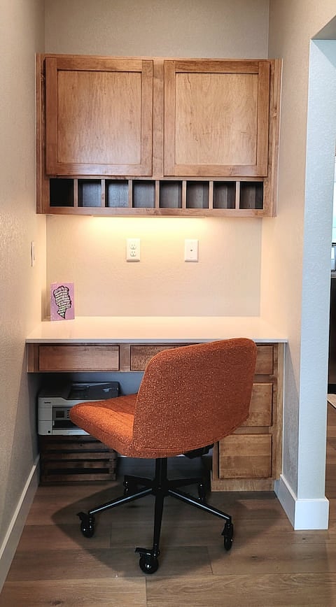 WFH space with criss-cross roller chair, wireless printer, electrical outlet, Gig-speed Ethernet jack, and various other office/craft supplies.