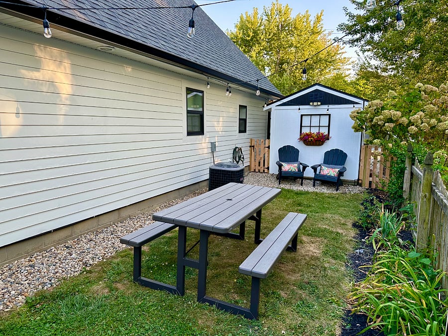 Beautiful fenced side yard with chairs, picnic table and gas grill.