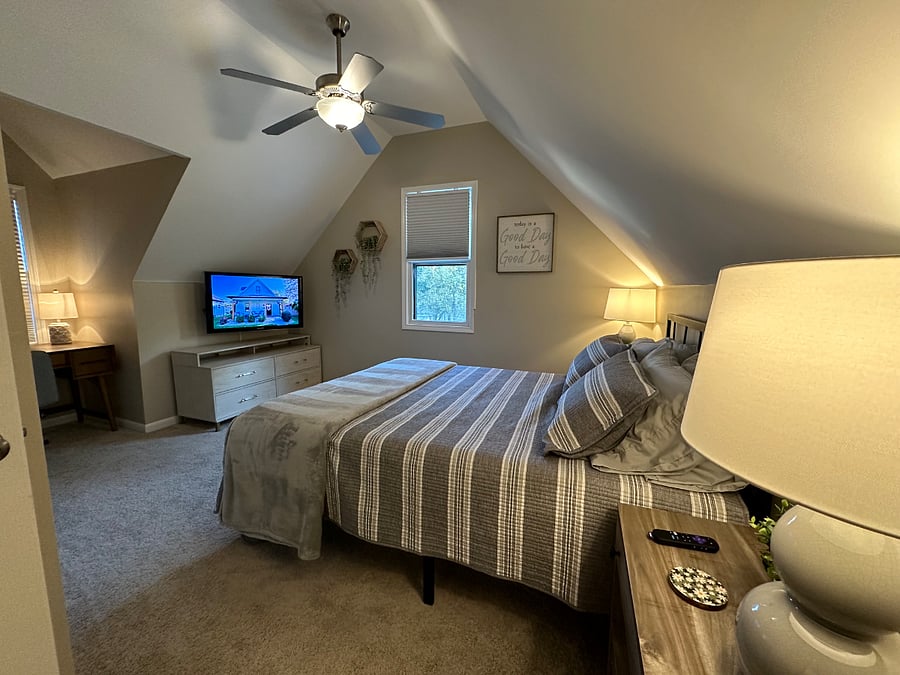 Upstairs queen bedroom is cozy and equipped with a workstation, 50 tv with Roku and nightstands with lamps and charging ports.