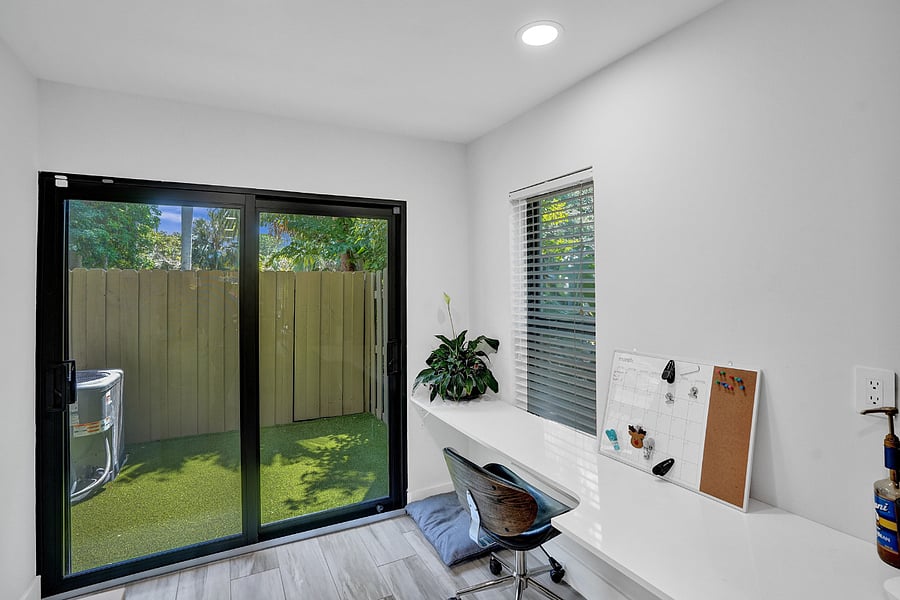 Bright lit Work space leading to fenced in small turf lined out door area.