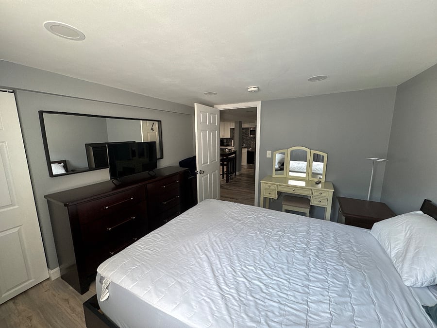 Bedroom TV, vanity, chest of drawers and entrance from the living room.