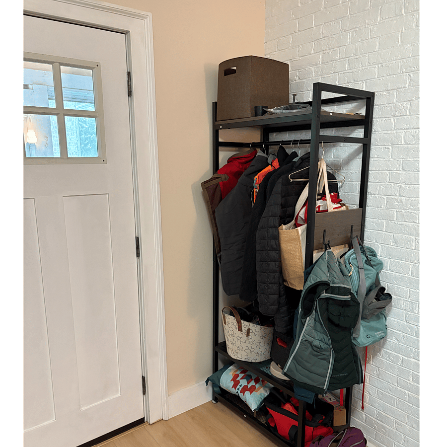 Coat rack with storage shelves just inside kitchen door.