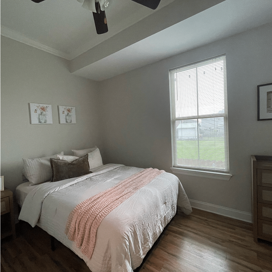 Front Bedroom with bathroom attached. The bedroom features a Queen Bed, nightstand with a night lamp, and a 4-drawer dresser.