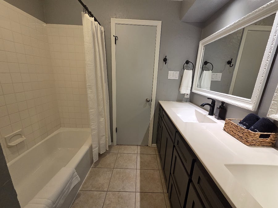 Bathroom with double sinks and bath/shower.