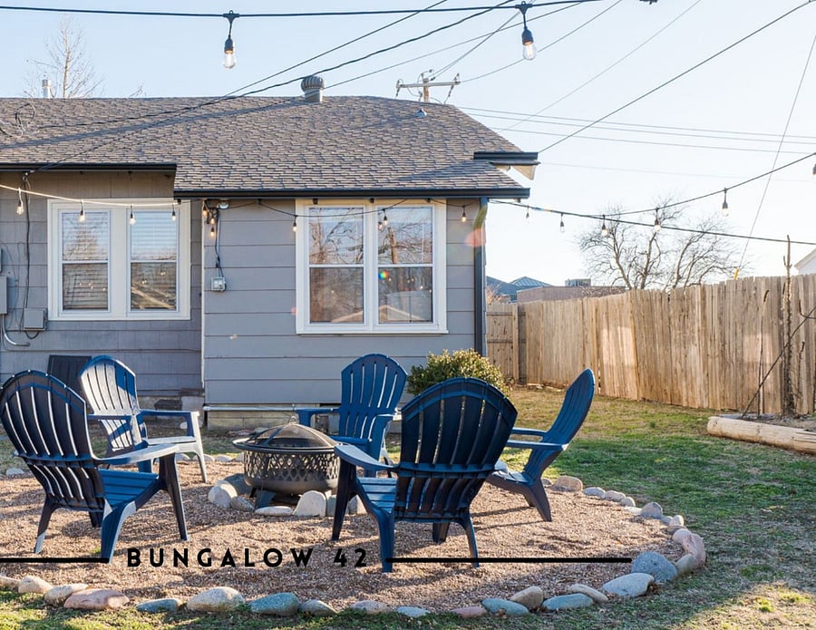 Large fire pit with enough seating for everyone, a huge fully fenced backyard, cafe lights and propane grill round out the space