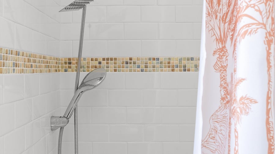 Close-up of rainfall and handheld shower head with tropical tile accents