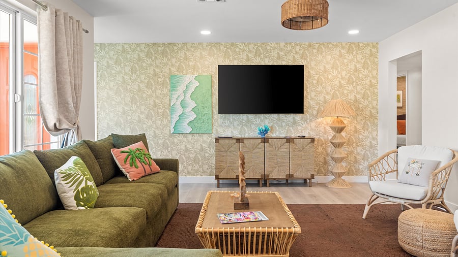 Comfort meets charm in this cozy media lounge featuring a deep sectional and tropical wallpaper backdrop. 65" Smart Tv
