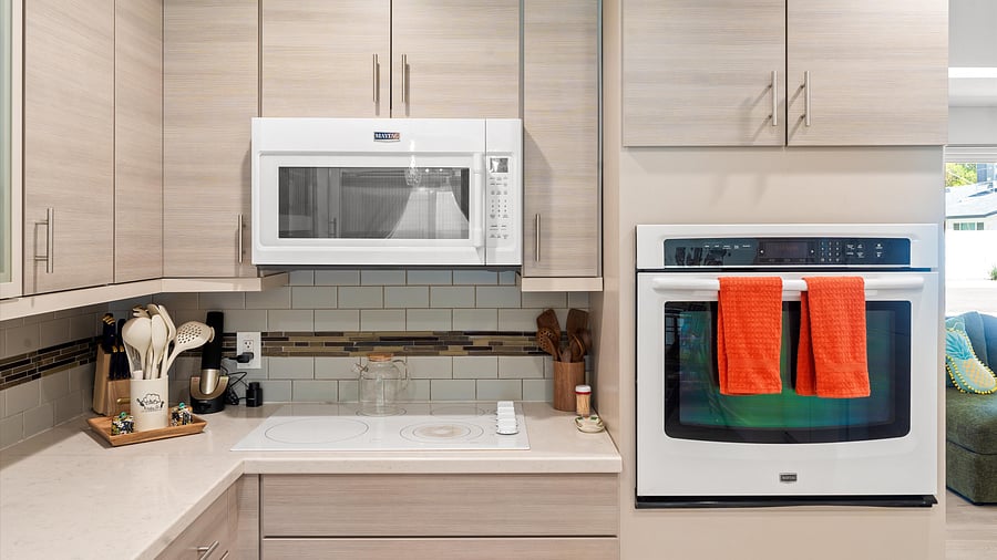 Fully stocked kitchen with soft wood cabinetry, built-in microwave, and playful details for effortless cooking.